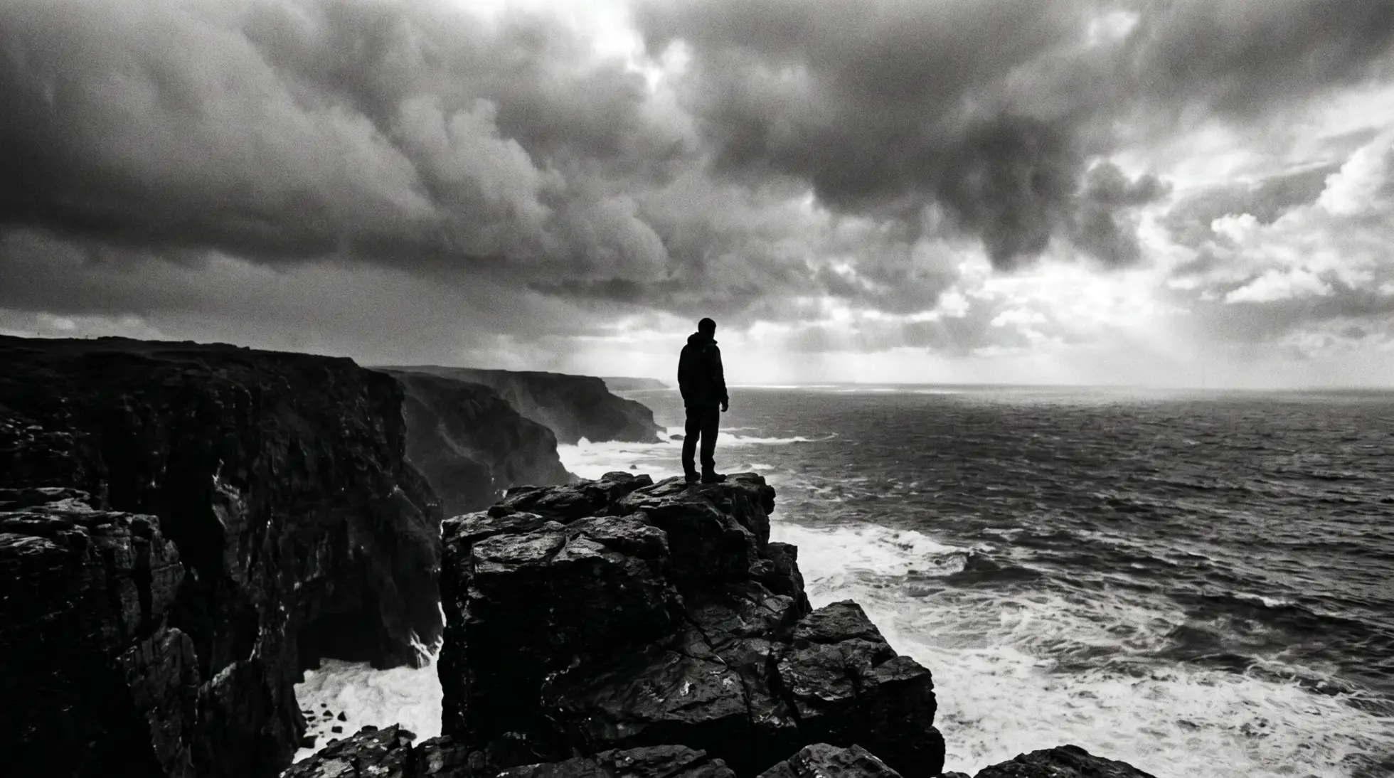 A lone figure on a storm lashed cliff edge above a heavy sea, on whether life is worth living