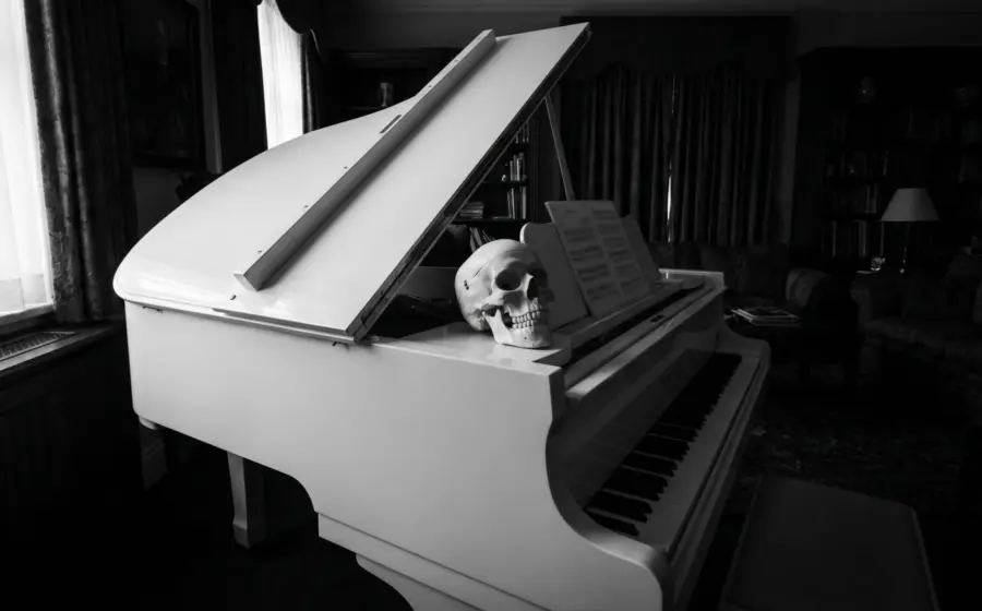 A human skull resting on a white grand piano beside sheet music, opening image on forensic anthropology of the skeleton