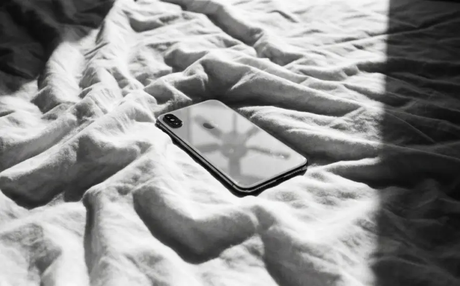 A switched off smartphone lying face down on a crumpled white bed sheet, opening image on 5 days without phone or feed