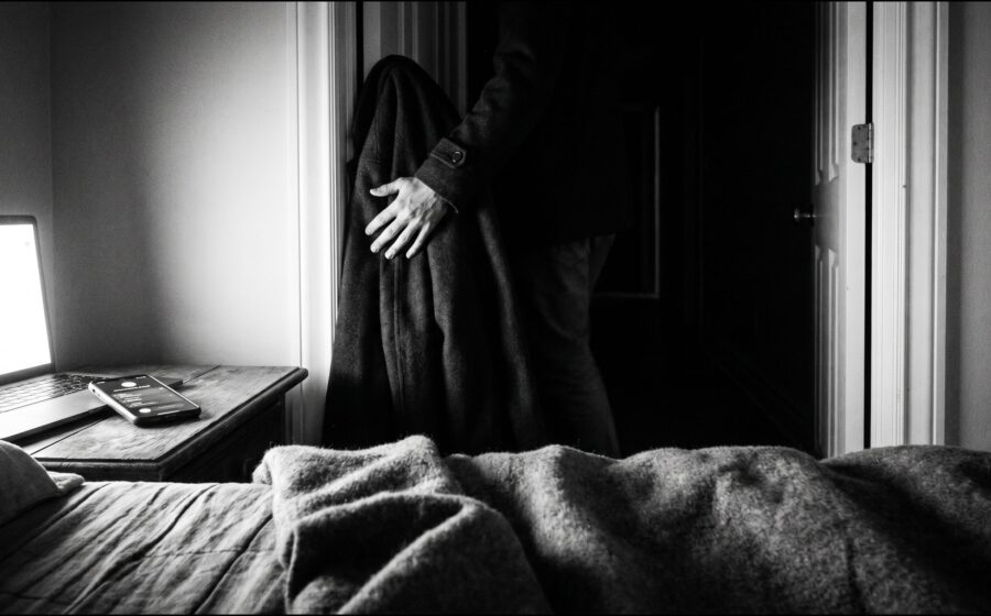 Schwarz-weiss: Gestalt verlässt ein klingelndes Schlafzimmer und geht in stille Dunkelheit hinaus