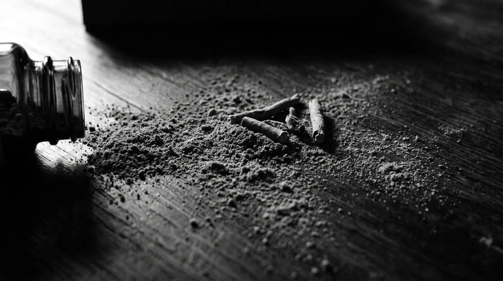 A tipped glass jar spilling ashwagandha root powder and opened capsules across dark wood, on cortisol and chronic stress